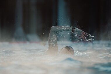Swimmer turning in the water during swimming, water splashing around them. | © sportingWOMEN