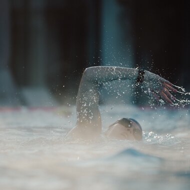 Swimmer turning in the water during swimming, water splashing around them. | © sportingWOMEN