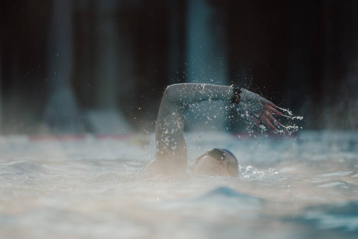 Swimmer turning in the water during swimming, water splashing around them. | © sportingWOMEN
