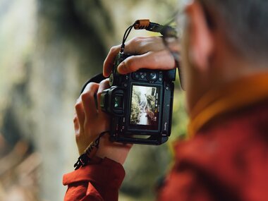 Person taking a photo of a natural scenery in a forest with a digital camera. | © Evolumina