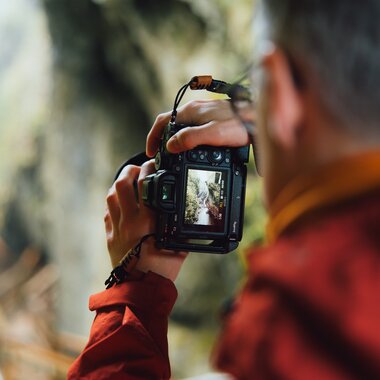 Person taking a photo of a natural scenery in a forest with a digital camera. | © Evolumina
