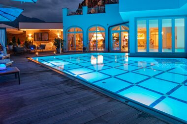 Luxury pool area at night with comfortable seating and lighting in an elegant accommodation. | © Nikolaus Faistauer Photography