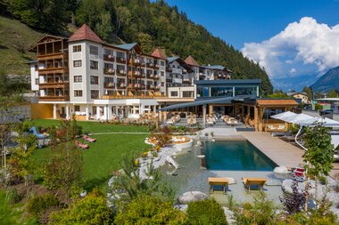 Modern hotel with pool, garden, and mountain view in a picturesque Alpine setting. | © Nikolaus Faistauer Photography