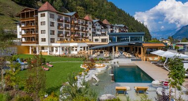 Modern hotel with pool, garden, and mountain view in a picturesque Alpine setting. | © Nikolaus Faistauer Photography