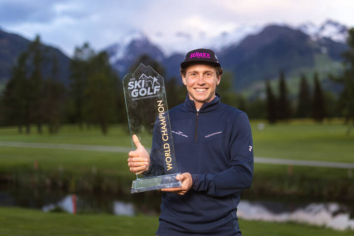 Person holding a trophy at the Ski&Golf World Championship 2025 in Zell am See-Kaprun, with mountain scenery in the background.