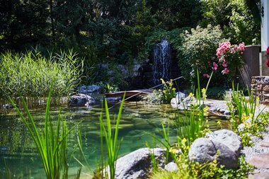 Garden with waterfall, pond, plants, and colorful flowers in a peaceful natural setting. | © 5*S Hotel Salzburgerhof Zell am See