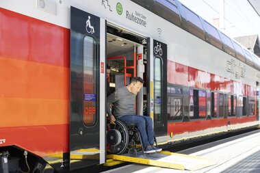 Person entering accessible train with wheelchair, marked with wheelchair and bicycle symbols. | © ÖBB | Harald Eisenberger