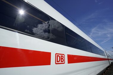 Close-up of a modern high-speed train of Deutsche Bahn with red stripe and DB logo against a blue sky. | © Emersleben Volker 
