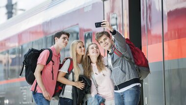 Group of young people taking a selfie at the train station in front of a train. | © Harald Eisenberger 