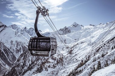 Cable car in snowy mountain landscape with high peaks and pine trees in the background. | © Kitzsteinhorn