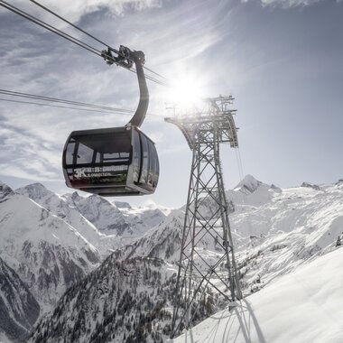 Cable car in the Alps with mountain peaks and a snow-covered valley in the background on a sunny day. | © Kitzsteinhorn