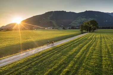 Possibly a gravel bike ride at sunrise through a lush landscape with mountains in the background. | © SalzburgerLand Tourismus