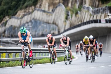 Cyclists participating in a race on a winding road with rocky cliffs in the background. | © Getty Images