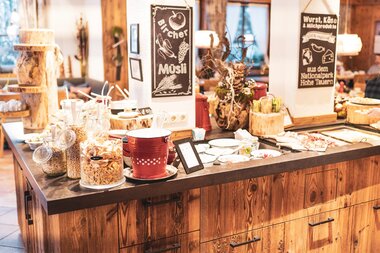 Breakfast buffet with various foods and drinks in a rustic wooden room. | © Zell am See-Kaprun Tourismus
