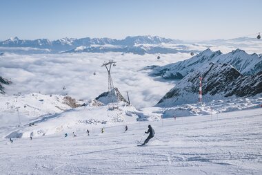 Skier on the slope with snowy mountains and clouds in the valley, at the Kitzsteinhorn ski resort in Kaprun. | © EXPA, Stefanie Oberhauser