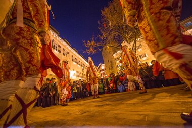 Traditional dance or celebration with dressed participants in Zell am See at night, with spectators in the background.