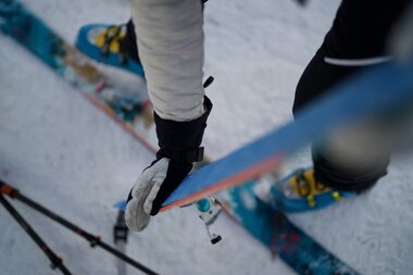 Close-up of a skier with gear standing on snow, with skis and poles. | © Zell am See-Kaprun Tourismus