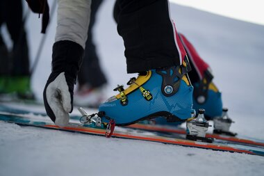 Close-up of a skier's blue ski boots and bindings on snow. | © Zell am See-Kaprun Tourismus