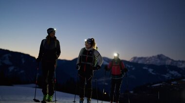 Nighttime skiing tour on the Ronachkopf with mountain landscape in the background. | © Zell am See-Kaprun Tourismus