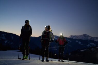 Nighttime skiing tour on the Ronachkopf with mountain landscape in the background. | © Zell am See-Kaprun Tourismus