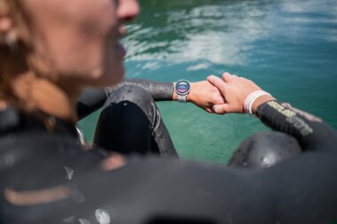 Person wearing a diving watch during an alpine triathlon at the water. | © Suunto Philipp Reiter