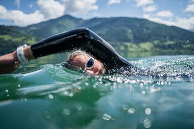 Person swimming in a lake with mountains in the background. | © Suunto Philipp Reiter