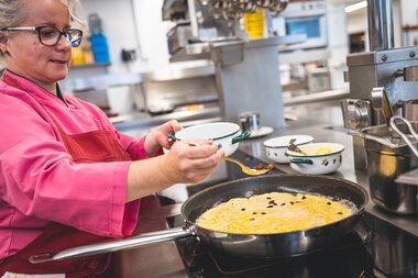 Person preparing Kaiserschmarrn in a kitchen, cooking batter in a frying pan. | © Zell am See-Kaprun Tourismus