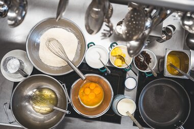 Preparation of a Kaiserschmarrn with eggs, flour, and other ingredients in a kitchen setting. | © Zell am See-Kaprun Tourismus