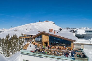 View of a modern mountain lodge in the snow with balcony and view of snowy landscape and ski resort in the background. | © Schmittenhöhe