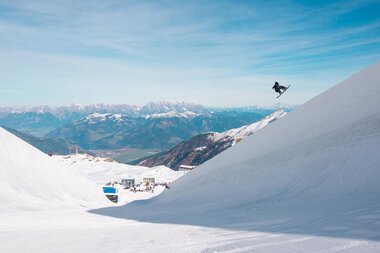 Person snowboarding on the snow slope of Kitzsteinhorn with mountains in the background. | © Kitzsteinhorn