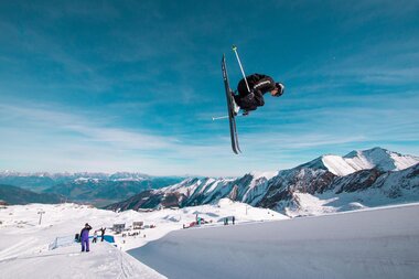Skier performed a jump in the snow park at Kitzsteinhorn with mountains in the background. | © Kitzsteinhorn