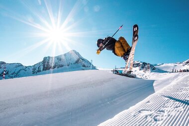 A snowboarder turns on a snowy slope under sunny weather in the mountains. | © Kitzsteinhorn