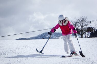 Person skiing on a snowy slope, wearing a helmet and goggles on a snowy day. | © Up adaptive sports 