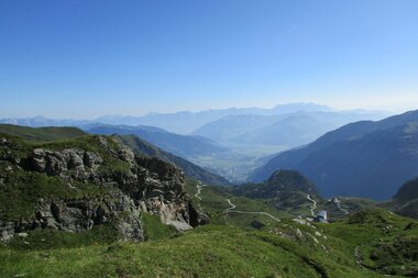 Panoramic view of mountain landscape with wide valley, green meadows, and hills under a clear blue sky. | © Zell am See-Kaprun Tourismus