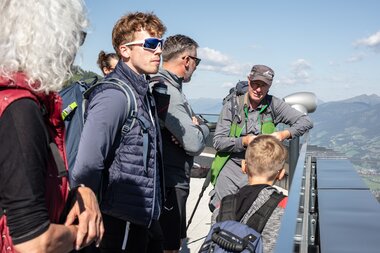 A group of people standing on a viewing platform overlooking the city and river with clear blue sky in the background. | © Kitzsteinhorn 