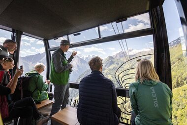 Group of people inside a gondola with views of mountain landscape and mountains in the background. | © Kitzsteinhorn