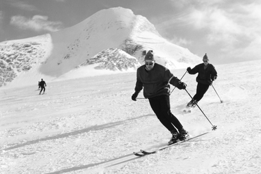 Historical black-and-white photo of skiers from the 1960s in front of a snow-covered mountain in the Kitzsteinhorn area. | © Gletscherbahnen Kaprun AG