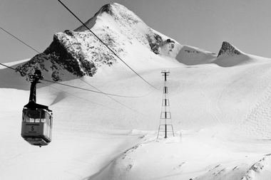 Historical photo of a summit cable car in snowy mountain landscape with cable and tower. | © Gletscherbahnen Kaprun AG