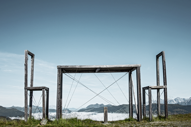 Art installation featuring large wooden frames in a rural mountain landscape. | © Schmittenhöhebahn