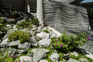 Outdoor art installation featuring rocks, plants, and a suspended fabric structure. | © Schmittenhöhebahn