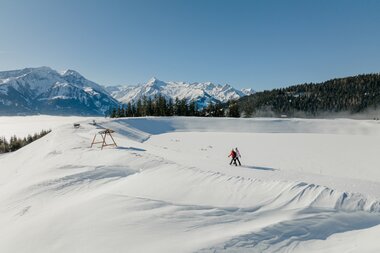 Winter scene on the Schmittenhöhe with snowshoe hikers against mountains and clear sky | © Zell am See-Kaprun Tourismus