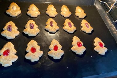 Baking tray with freshly baked gingerbread shaped like trees, decorated with red and purple toppings. | © Zell am See-Kaprun Tourismus