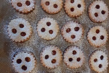 Small cookies with icing and chocolate chips, arranged on a baking sheet. | © Zell am See-Kaprun Tourismus
