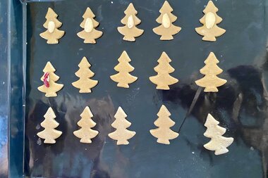 Unbaked cookies shaped like Christmas trees are placed on a baking sheet. | © Zell am See-Kaprun Tourismus