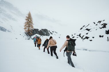 Group of hikers walking in a snowy mountain landscape with winter conditions. | © manueldietrichphotography