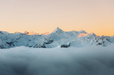 Mountains at sunrise with snow-covered peaks and light fog in the foreground. | © manueldietrichphotography