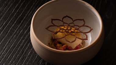 Dessert with salted caramel ice cream, miso, and a decorative flower drawing on the ice cream in a bowl. | © Bastian Knapp - Restaurant Artis