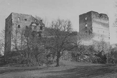 Castle ruins with two remaining towers, surrounded by trees and an unpaved path, historical black-and-white scene. | © Burg Kaprun 