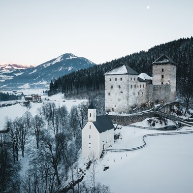 Santa Maria on a snowy hill with a castle in the background, set in a winter landscape in Kaprun. | © Zell am See-Kaprun Tourismus