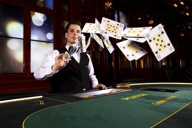 Young person playing cards at a casino with flying playing cards. | © Casinos Austria